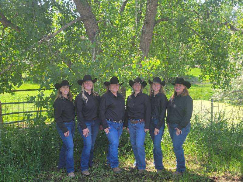 Six riders of Rocky Mountain Freedom Riders standing under cottonwood trees in matching black western shirts